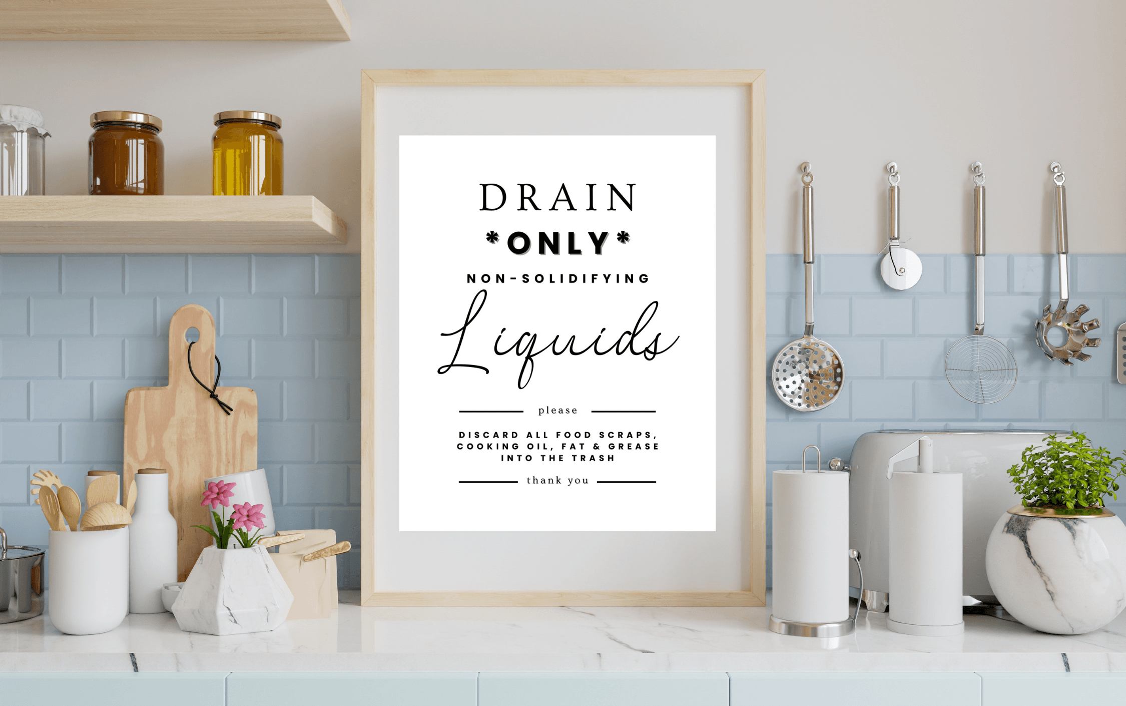A kitchen counter with a framed poster that gives tips about what to safely put down the drain